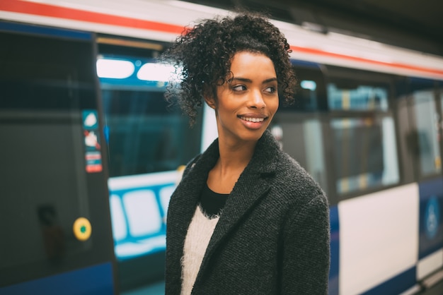 Szczęśliwa młoda murzynka wśrodku staci metru czeka pociąg