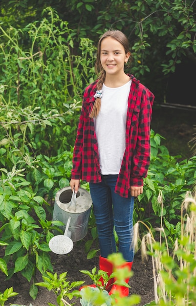 Szczęśliwa młoda nastolatka pozuje z konewką w ogrodzie