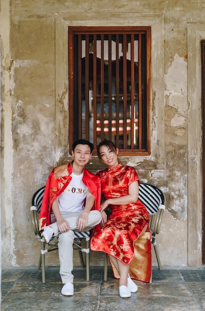 Szczęśliwa młoda para Azjatów kocha się w chińskich tradycyjnych strojach - czerwony jest głównym kolorem tradycyjnego święta, w tym ślubu w Chinach.