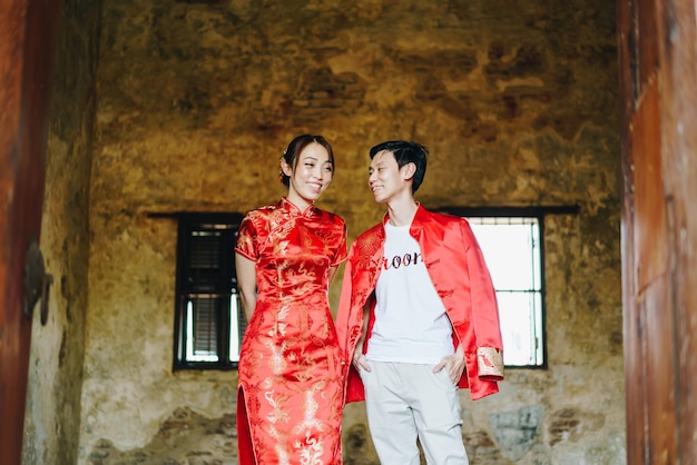 Szczęśliwa młoda para Azjatów kocha się w chińskich tradycyjnych strojach - czerwony jest głównym kolorem tradycyjnego święta, w tym ślubu w Chinach.