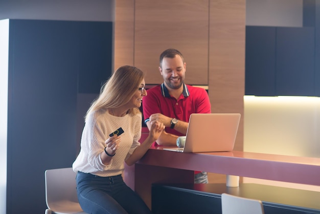 szczęśliwa młoda para kupująca online za pomocą laptopa, komputera i karty kredytowej w swojej luksusowej willi