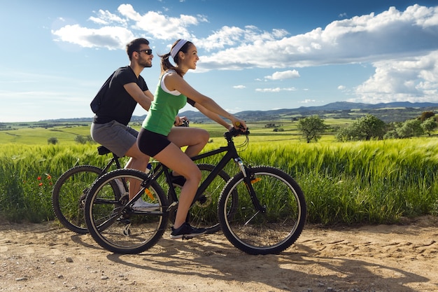 Szczęśliwa młoda para na rowerze na wsi