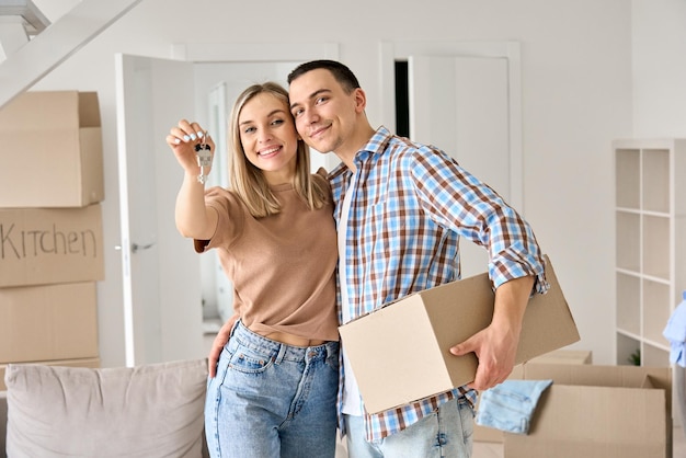 Zdjęcie szczęśliwa młoda para po raz pierwszy właściciele domów trzymając klucze w nowym domu