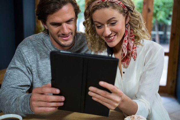 Szczęśliwa młoda para przy użyciu komputera typu tablet przy stole w kawiarni