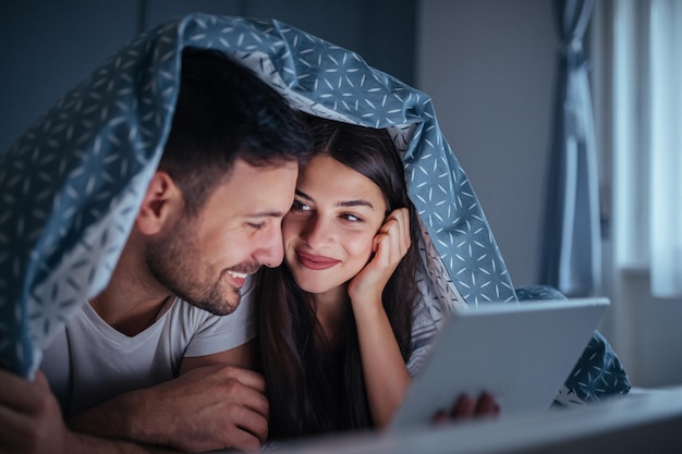 Szczęśliwa młoda para razem surfuje po Internecie w nocy