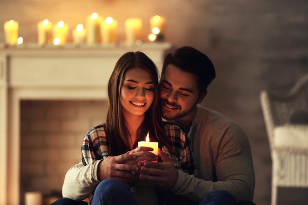 Szczęśliwa młoda para z płonącą świecą w domu
