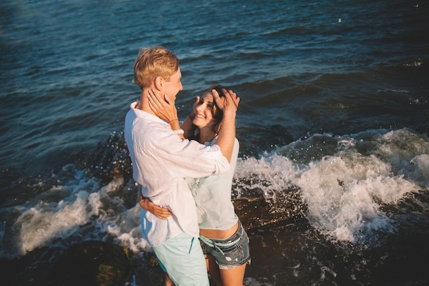 Szczęśliwa młoda para zakochana na tle morza spaceruj po plaży na tle błękitnego nieba i baw się w letni dzień