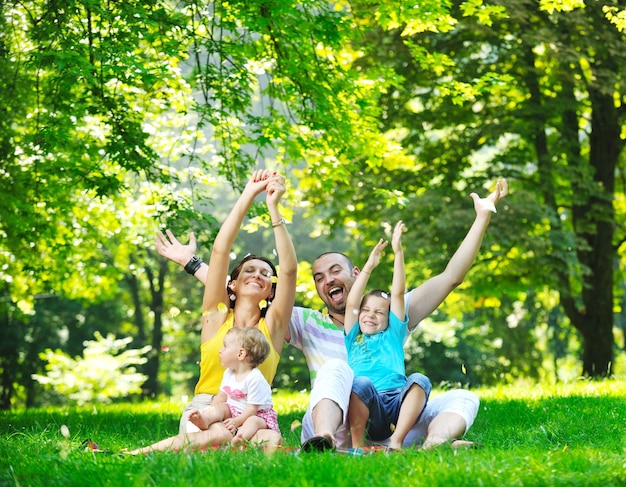 Szczęśliwa młoda para ze swoimi dziećmi bawić się w pięknym parku na świeżym powietrzu w przyrodzie
