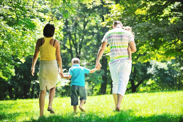 Szczęśliwa młoda para ze swoimi dziećmi bawić się w pięknym parku na świeżym powietrzu w przyrodzie