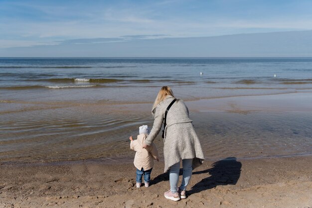 Szczęśliwa młoda rodzina bawi się na plaży i skacze o zachodzie słońca