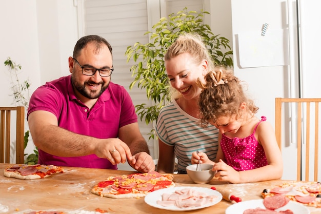 Szczęśliwa młoda rodzina gotuje domową pizzę