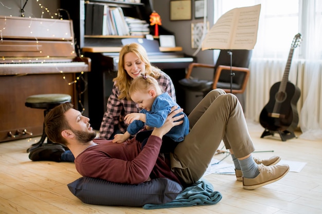 Szczęśliwa młoda rodzina gra na podłodze w rustykalnym pokoju