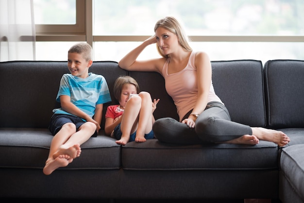 Szczęśliwa młoda rodzina gra razem z tabletem w domu siedząc na kanapie