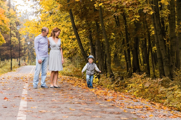 Szczęśliwa młoda rodzina idąc drogą na zewnątrz w zieleni