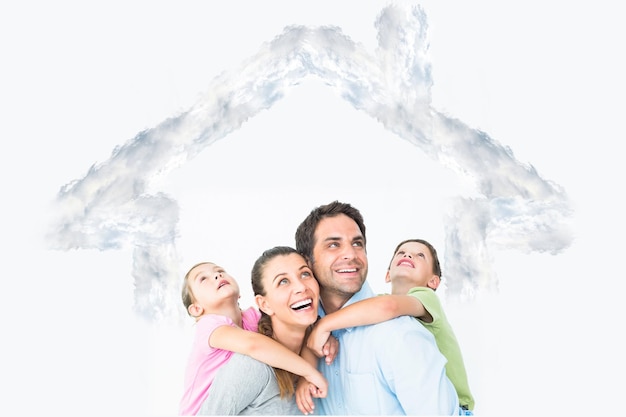 Zdjęcie szczęśliwa młoda rodzina patrząc razem na zarys domu w chmurach