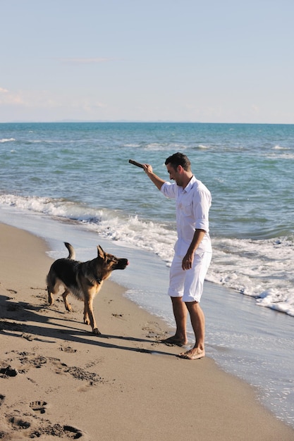 szczęśliwa młoda rodzina w białych ubraniach bawi się i bawi z pięknym psem na wakacjach na pięknej plaży