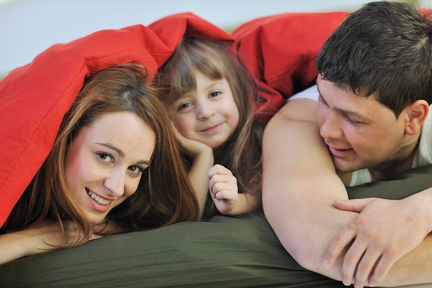 Zdjęcie szczęśliwa młoda rodzina w domu relaksuje się w łóżku