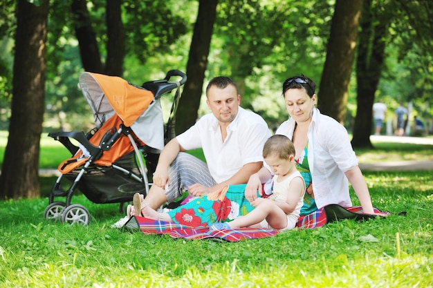 Szczęśliwa młoda rodzina w parku odpoczywa i bawi się z kobietą w ciąży