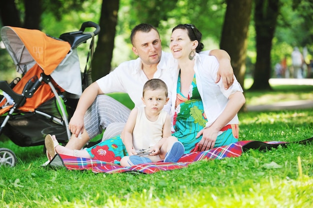 Szczęśliwa młoda rodzina w parku odpoczywa i bawi się z kobietą w ciąży