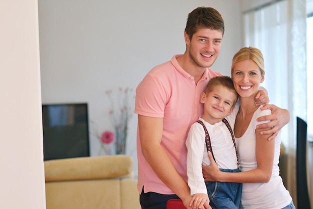 Zdjęcie szczęśliwa młoda rodzina z dziećmi w jasnym nowoczesnym salonie baw się dobrze i wygląda na duży płaski telewizor lcd