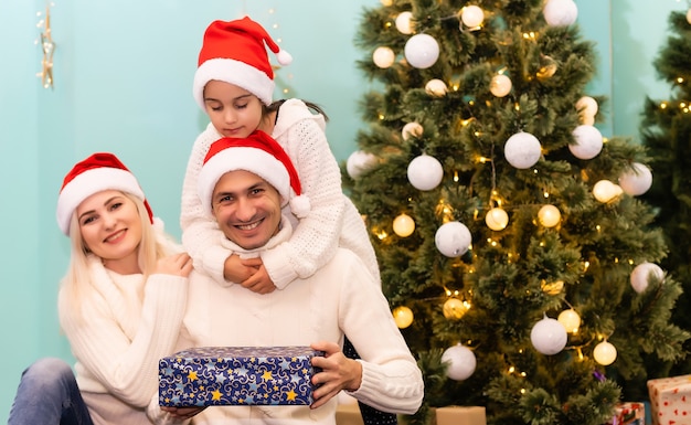szczęśliwa młoda rodzina z jednym dzieckiem trzymającym prezent świąteczny i uśmiechającym się do kamery