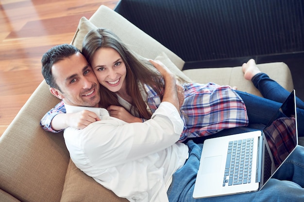 szczęśliwa młoda zrelaksowana para pracująca na laptopie w nowoczesnym wnętrzu domu