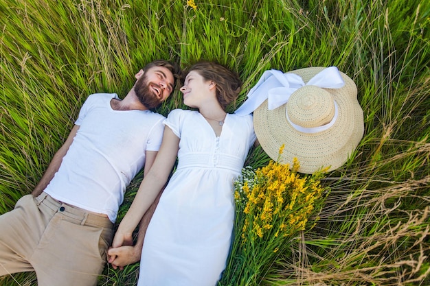 Szczęśliwa młoda zrelaksowana zakochana para leżąca na trawie nad głową