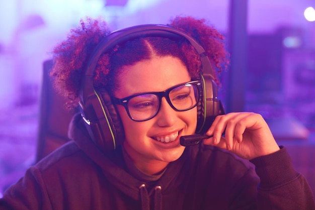 Szczęśliwa nastolatka-gracz i słuchawki w domu do e-sportowych gier online lub wirtualnych zawodów Żeński streamer komputerowy przekaz na żywo i gry dla uśmiechu w neonowym oświetleniu nocna technologia lub gen z