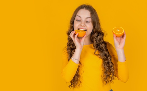 Szczęśliwa nastolatka je pomarańczowe owoce na żółtym tle