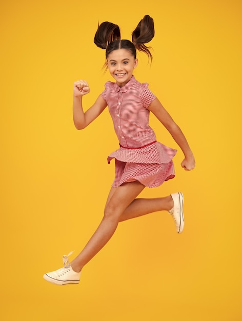 Szczęśliwa nastolatka pozytywne i uśmiechnięte emocje nastolatki Nastolatka skacze na całej długości jej figlarna nastolatka, która dobrze się bawi i skacze na białym tle na żółtym tle
