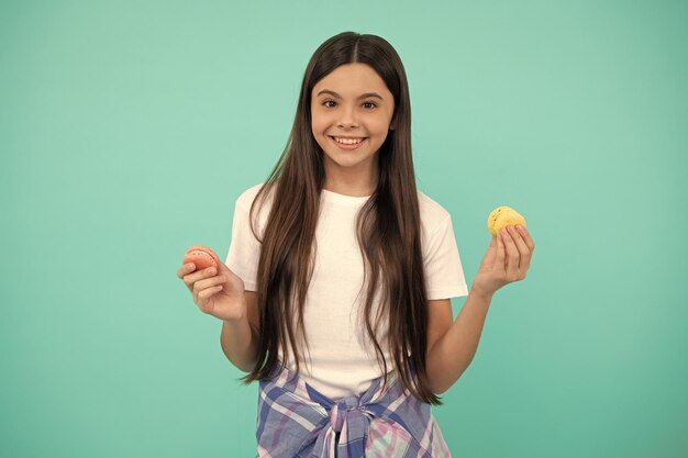 Szczęśliwa nastolatka trzyma francuskie ciasteczka makaronikowe lub ciasteczka makaronikowe