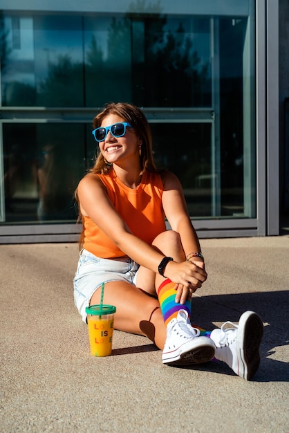 Zdjęcie szczęśliwa nastolatka w jasnych kolorowych skarpetkach tęczowych i okularach przeciwsłonecznych modne nastolatki pokolenia z