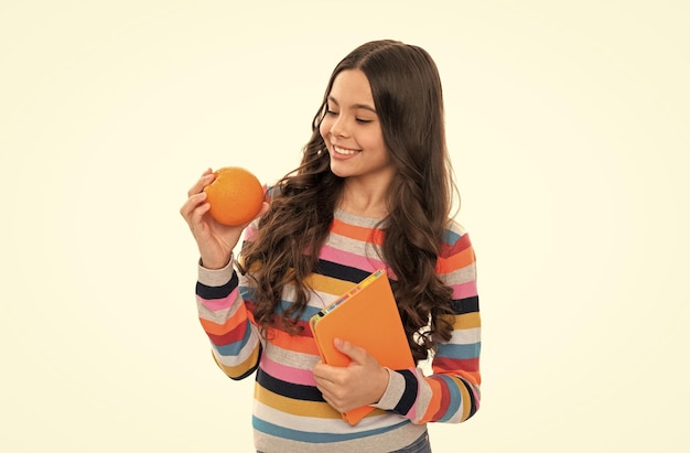 Szczęśliwa nastolatka w swetrze z pomarańczowymi owocami i zeszytem szkolnym na białym tle z powrotem do szkoły