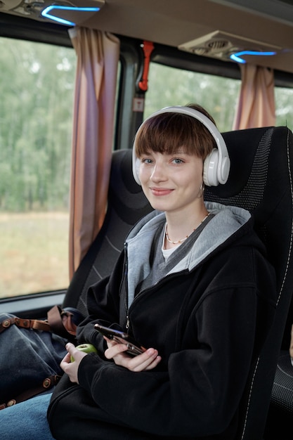 Szczęśliwa nastolatka ze smartfonem słuchająca muzyki w słuchawkach