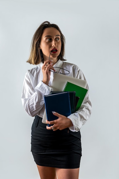 Szczęśliwa nauczycielka lub bizneswoman trzymająca książki i uśmiechająca się na tle