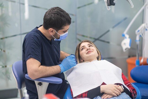 Szczęśliwa pacjentka patrząca na dentystę w masce medycznej uśmiechająca się