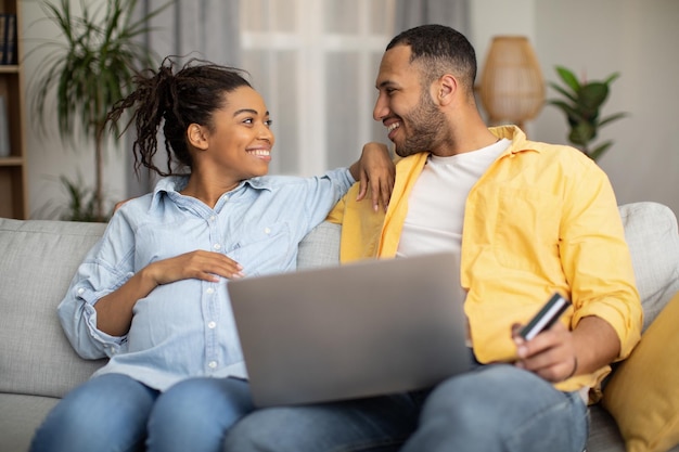 Szczęśliwa Para Afrykańska, Korzystająca Z Laptopa, Przeglądającego Internet, Siedząc W Domu