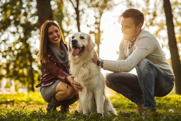 Szczęśliwa para bawi się z psem w parku