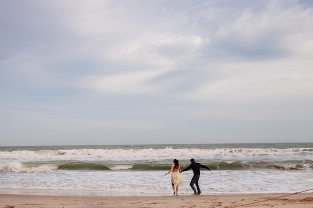 Szczęśliwa para biegnie razem na plaży Widok na morze i piaszczysta plaża?