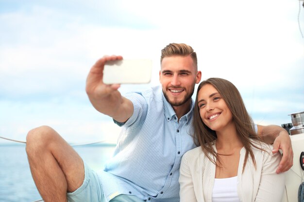 Szczęśliwa para biorąca selfie po propozycji zaręczyn na żaglówce, relaks na jachcie na morzu.