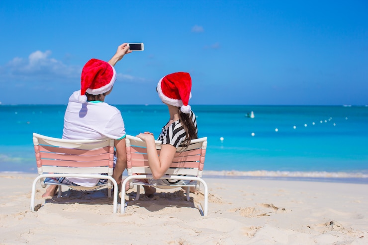 Zdjęcie szczęśliwa para jest ubranym santa kapelusz przy karaibską plażą