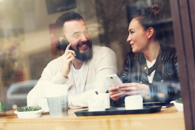 szczęśliwa para korzystająca z telefonów w restauracji?