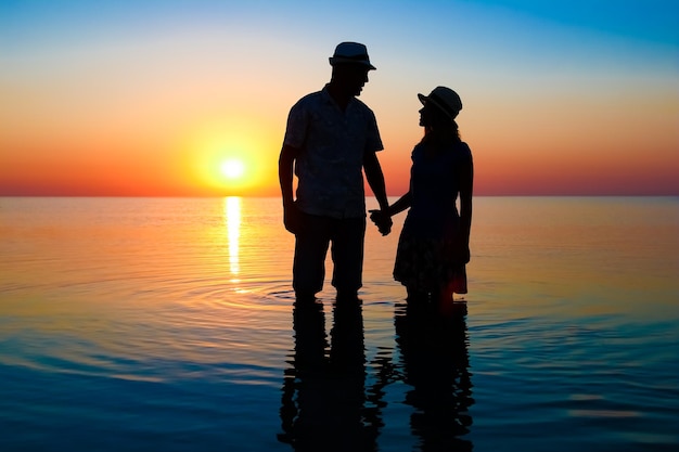 Szczęśliwa para nad morzem o zachodzie słońca na sylwetka podróży w przyrodzie