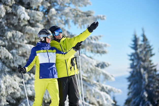 Szczęśliwa para narciarzy pozuje na nartach przed jazdą na nartach w ośrodku narciarskim