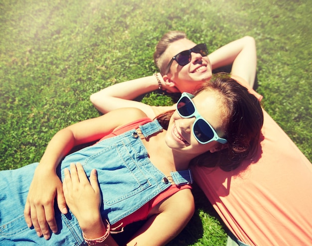 Zdjęcie szczęśliwa para nastolatków leżąca na trawie latem