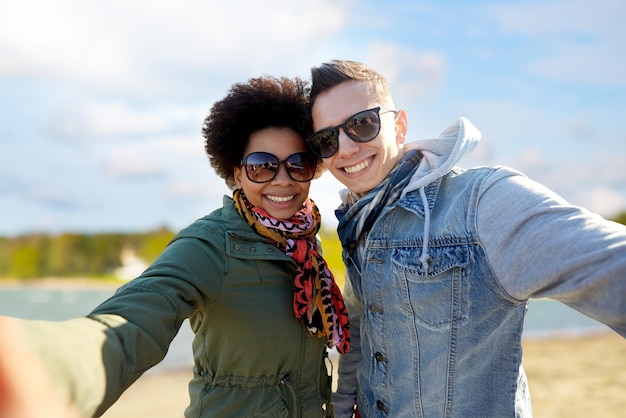 Szczęśliwa para nastolatków robiąca sobie selfie na plaży.