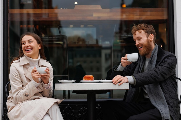 Szczęśliwa para pije kawę i śmieje się rozmawiając ze sobą