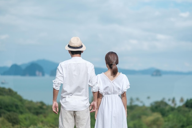 Szczęśliwa para podróżnik w białej koszuli i sukience ciesz się pięknym widokiem Turyści stojący i relaksujący się nad oceanem podróżują razem kochają koncepcję lata i wakacji