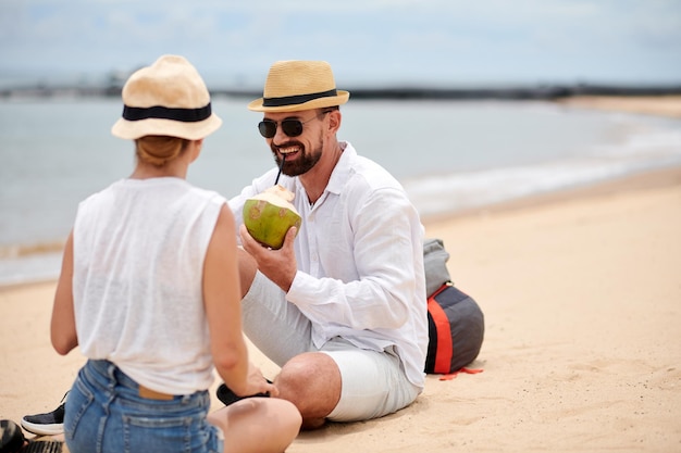 Szczęśliwa para relaksuje się na plaży z kokosami