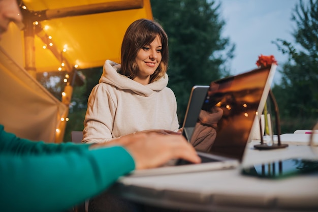 Szczęśliwa para rodzinna freelancerów pracujących na laptopie w przytulnym namiocie glampingowym w letni wieczór Luksusowy namiot kempingowy na wakacje na świeżym powietrzu i wakacje Koncepcja stylu życia